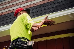A contractor installing gutters on a home.