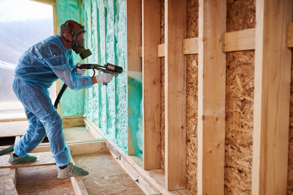 Technician installing spray foam insulation in home to improve insulation r-value of home