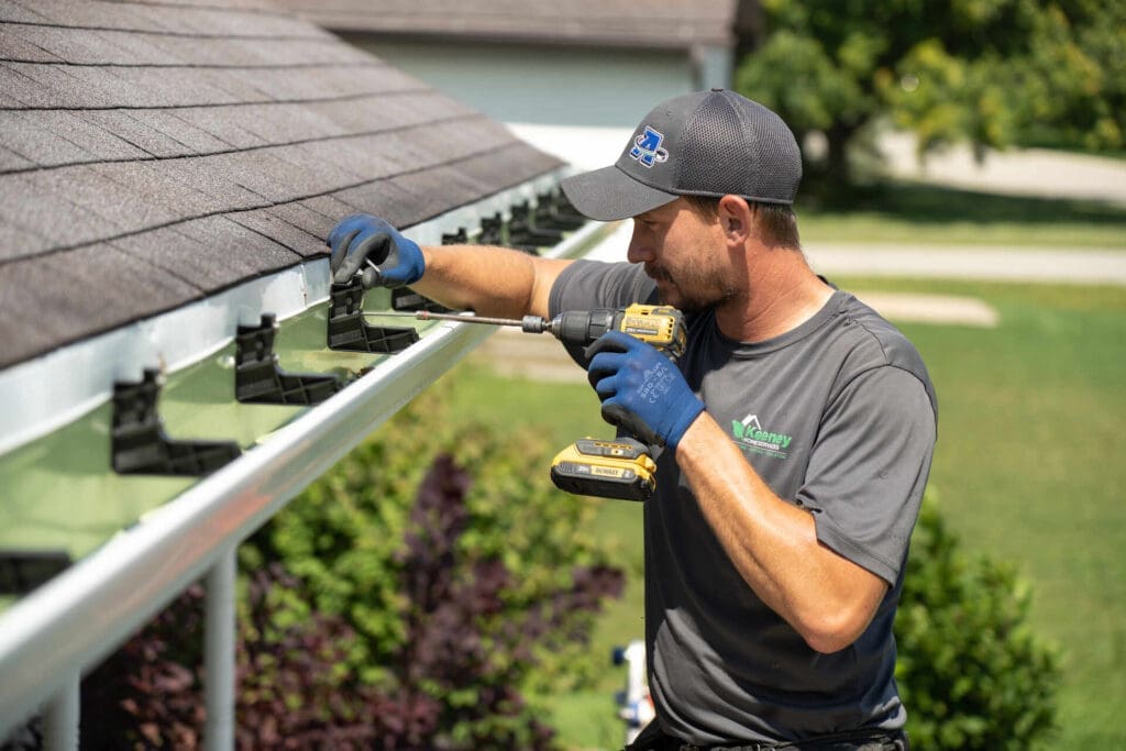Larson & Keeney Home Services technician installing a gutter system on a residential roof